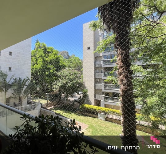 אדם עומד במרפסת עם רשת נגד יונים